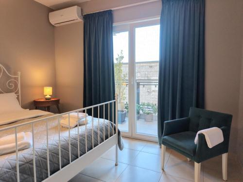 a bedroom with a bed and a chair and a window at Luce Apartment in Shkodër