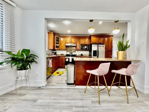 a kitchen with wooden cabinets and pink chairs at Seattle 2nd Floor House with 2 Queen Bedrooms and Extra Sofa Bed Located 10 minutes from SeaTac Airport and 20 minutes from Downtown in Seattle