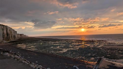 a sunset over the ocean with a rocky beach at Le temps des vacances in Vaudricourt