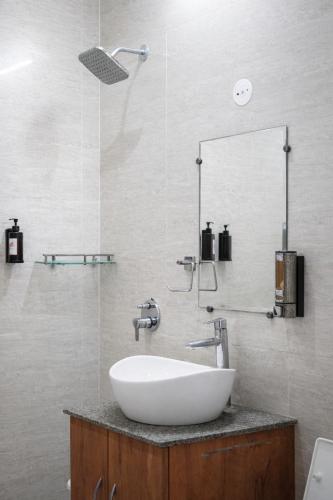 a bathroom with a white sink and a shower at Saffron Inn - Near India Expo Mart in Greater Noida