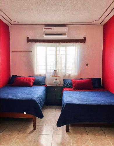 two beds in a room with red walls at La prieta linda in Tamasopo