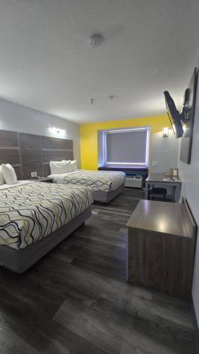 a hotel room with two beds and a flat screen tv at Desert Inn Tucumcari in Tucumcari