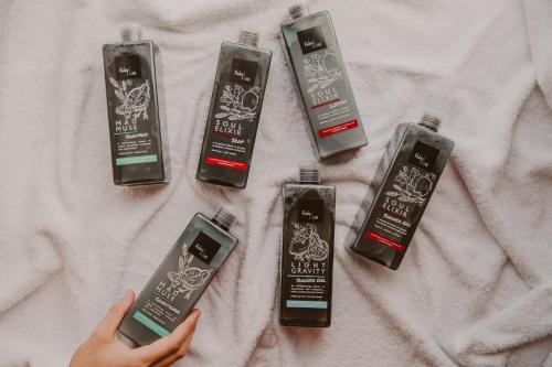 a person holding a cell phone next to four hair products at Ruby Zoe Hotel London by IHG in London