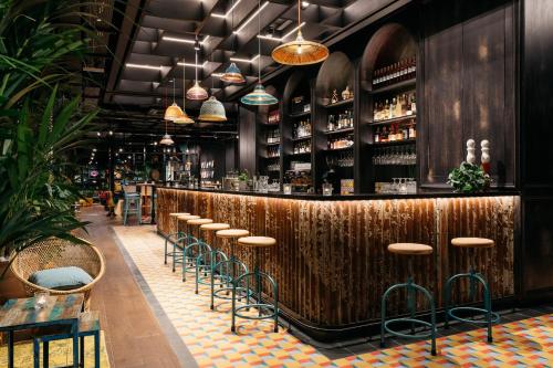 a restaurant with a wooden bar with stools at Ruby Zoe Hotel London by IHG in London