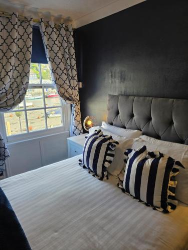 a bedroom with a bed with striped pillows and a window at Harbour Moon Inn in Looe
