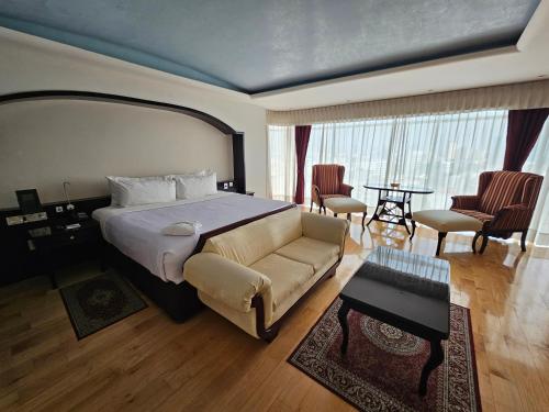 a bedroom with a bed and a couch and a table at BelAir Unique a Wyndham Hotel in Mexico City