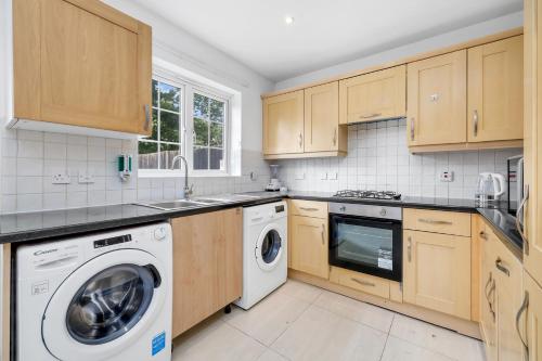 a kitchen with wooden cabinets and a washer and dryer at Riverview, studio style room near station R3 in London