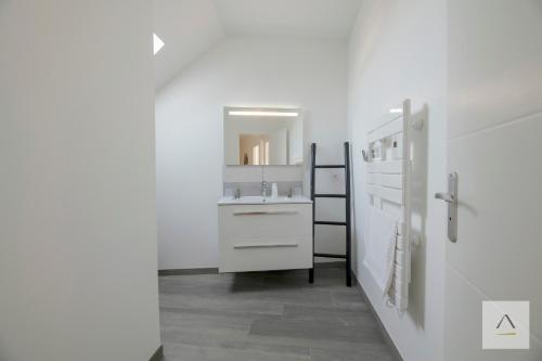a white bathroom with a sink and a mirror at Ker Lilouane in Hirel