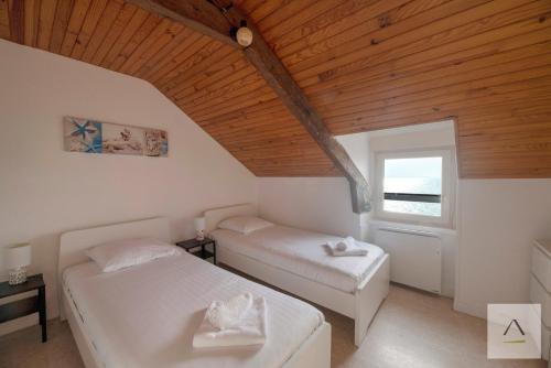 two beds in a room with a wooden ceiling at La Maison de Pêcheurs in Cancale
