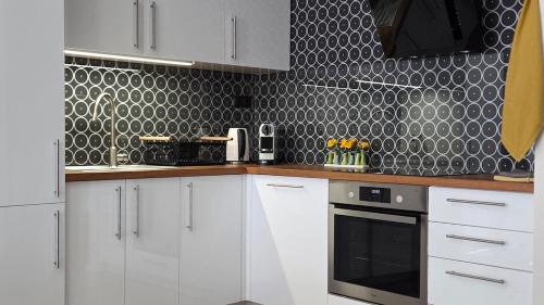 a kitchen with white cabinets and black and white tiles at MoMa Homes Kecskemét in Kecskemét