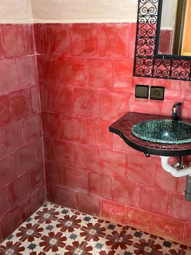 a red tiled bathroom with a sink and a mirror at auberge atlas tamatertt in Imlil