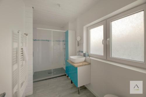 a white bathroom with a sink and a window at La Cabane à Hirel in Hirel