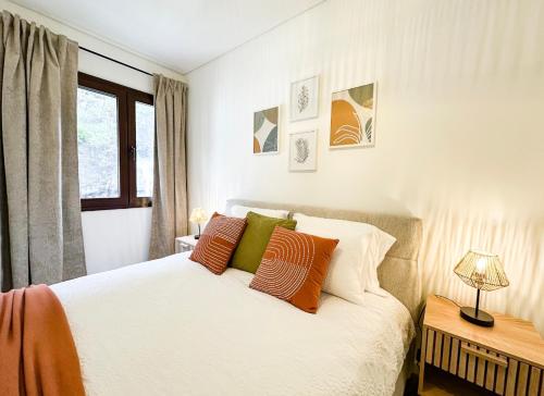 a bedroom with a white bed with orange and green pillows at Ninho da Ribeira in Ribeira Brava
