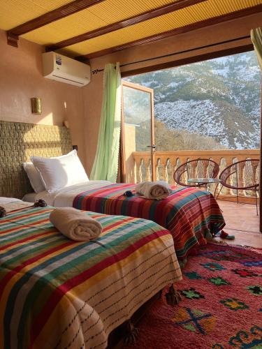 two beds sitting in a room with a window at auberge atlas tamatertt in Imlil