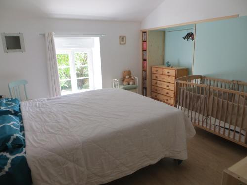 a bedroom with a white bed and a crib at Les Lilas in Saint-Clair