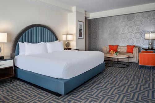 a bedroom with a large bed and a living room at Colcord Hotel Oklahoma City, Curio Collection by Hilton in Oklahoma City