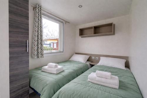 two beds in a room with green sheets and towels at Mobilhome L'Instant Vacances - La Plage in Mimizan-Plage