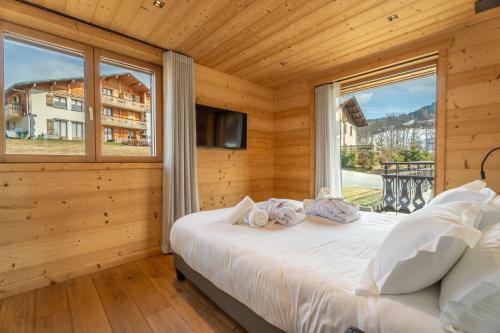 a bedroom with a bed and a large window at Appartement Gondola & Spa - MultiPass in Les Gets