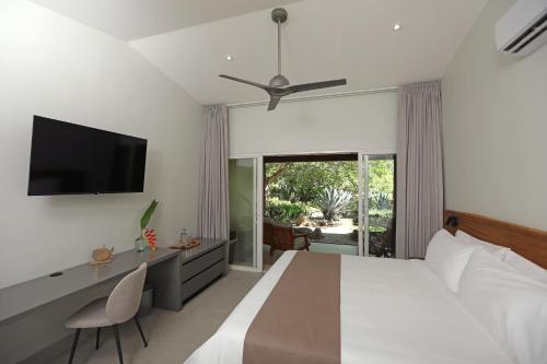 a bedroom with a bed with a television and a desk at OPacifico Hotel Boutique in Naranjo