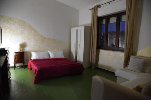 a bedroom with a bed and a couch and a window at Casa Luisa in Sarroch
