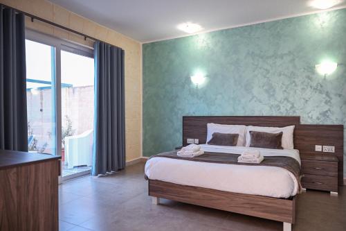 a bedroom with a bed and a large window at Ta' Battista B&B with Pool - Gozo in Xewkija