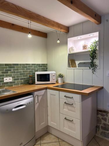 a kitchen with white cabinets and a white microwave at La Maison dans les Nuages in Sécheras
