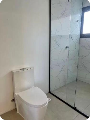 a bathroom with a toilet and a glass shower at Suíte completa com cozinha próximo ao mar in Torres