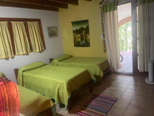 a room with three beds with green sheets on it at Casa de Piedra in El Rodeo
