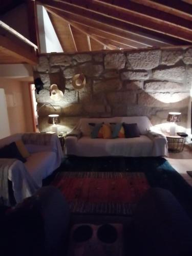a living room with two couches and a stone wall at Sorte do Jugo - Lakeside cottage with private beach in Vieira do Minho