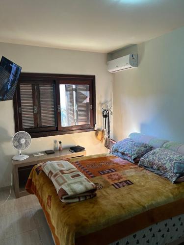 a bedroom with a bed with a desk and a window at Pedra Branca Retreat in Garopaba