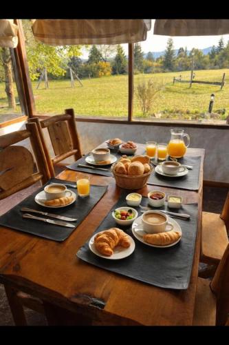 a table with croissants and food and glasses of orange juice at Lodge Ruta 71 in Trevelín