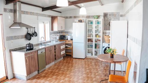 a kitchen with a table and a white refrigerator at Casa de la Abuela - Encanto rural para grupos in Campofrío
