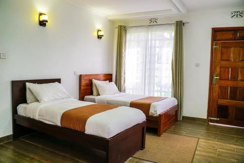 a hotel room with two beds and a window at Pacificas place in Eldoret