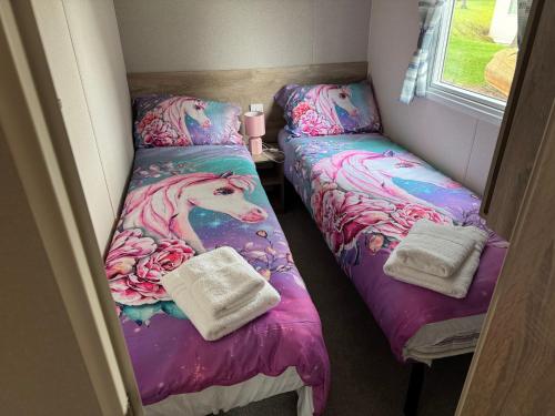 two beds in a room with a unicorn on them at West Lawn 47 Haggerston Castle Paddock Views in Berwick-Upon-Tweed