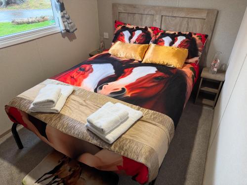 a bedroom with a bed with a cow blanket and towels at West Lawn 47 Haggerston Castle Paddock Views in Berwick-Upon-Tweed
