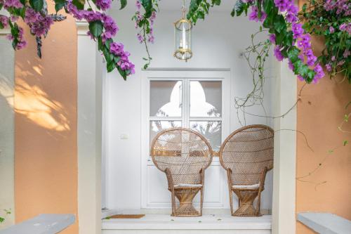 two wicker chairs in front of a door with purple flowers at Luksuzni apartmaji v centru Portoroža z vrtom in parkiriščem - Luxury Apartments in Portoroz Center with Garden & Parking in Portorož