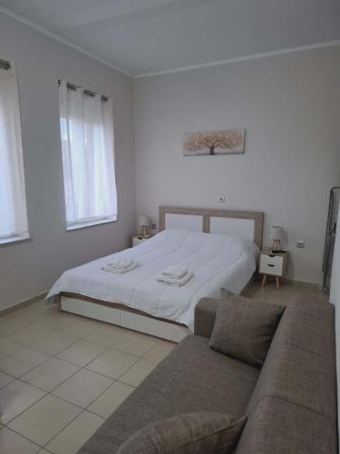 a white bedroom with a bed and a couch at Studio Panos 2 in Mytilene