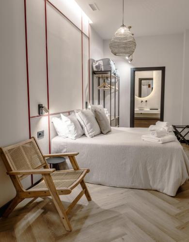 a bedroom with a bed and a chair and a mirror at Castelar Urban Suites in Badajoz
