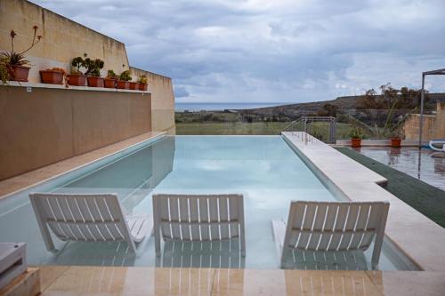 two chairs and a swimming pool on a house at Ta' Battista B&B with Pool - Gozo in Xewkija