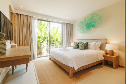 a bedroom with a bed and a desk and a window at Trichada Essence in Ban Pak Lak