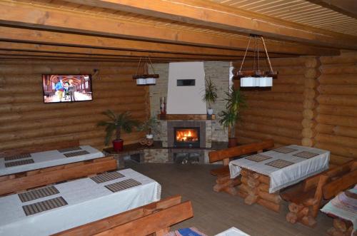 a living room with a fireplace in a log cabin at Sadyba Pikuy in Bilasovytsya
