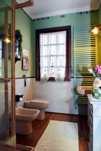 a bathroom with a toilet and two sinks and a window at B&B Al Roncaccio in Calco