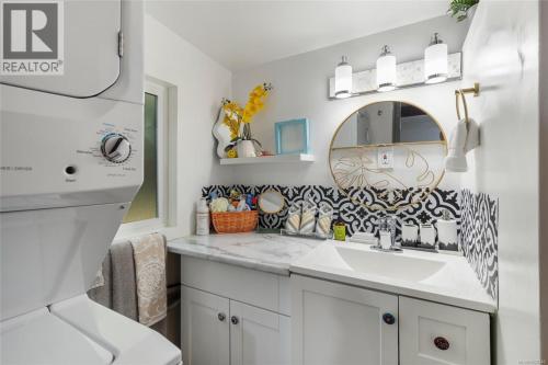a white bathroom with a sink and a mirror at Nesting Ravens cottage in Nanaimo