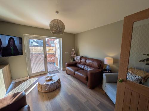 a living room with a leather couch and a table at Beachwood in Skegness