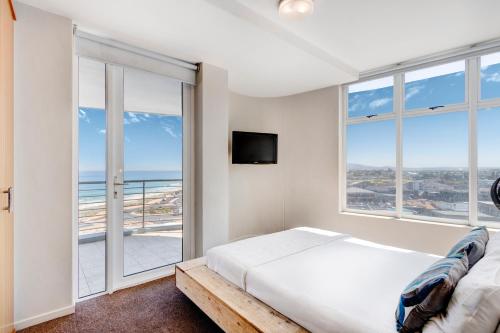 a bedroom with a bed and a large window at Cape Town, Blouberg Beachfront Luxury Apt - Kite Beach in Bloubergstrand
