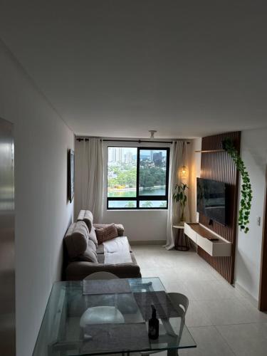 a living room with a couch and a glass table at Flat aconchegante com vista pro açude in Campina Grande
