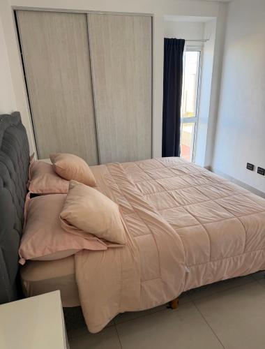 a bedroom with a bed with pillows and a window at Brisa del mar in Comodoro Rivadavia