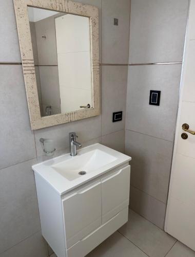 a white bathroom with a sink and a mirror at Brisa del mar in Comodoro Rivadavia