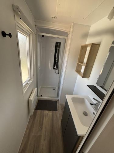 a small bathroom with a sink and a mirror at Mobil Home 6 personnes camping 4 etoiles Bonne Anse la Palmyre in Les Mathes