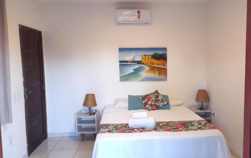 a bedroom with a bed and a painting on the wall at Pousada Ello in São Miguel do Gostoso